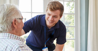 Male Care Worker serving dinner to a senior at home